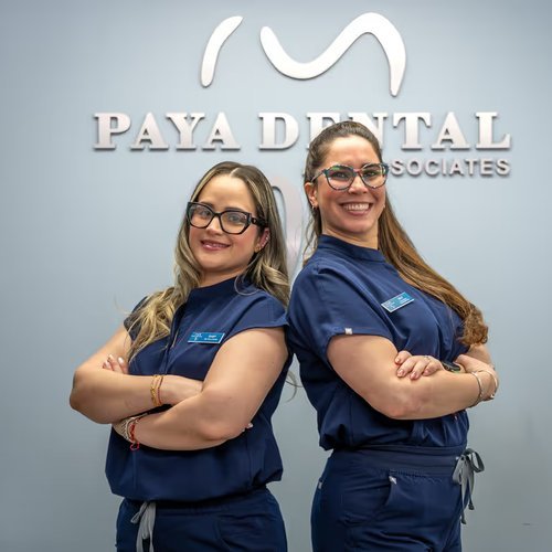 Two Paya Dental team members in front of the office logo