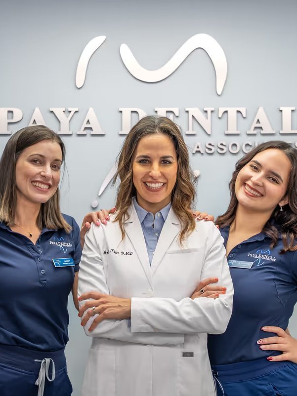 Dr. Anabel Paya with two Paya Dental team members in front of the office logo