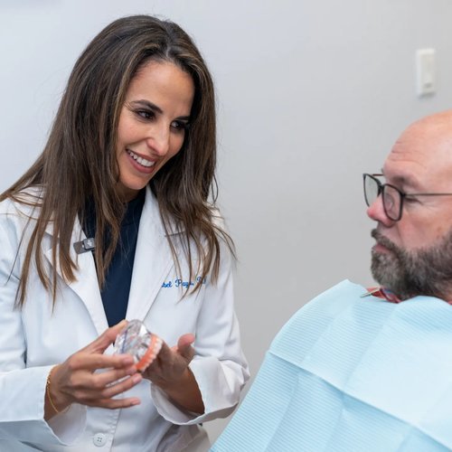 Dentist showing an implant model to a patient